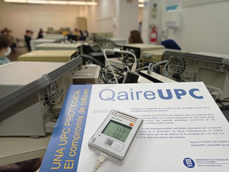 A QAireUPC poster and air-quality monitor in a university electronics lab